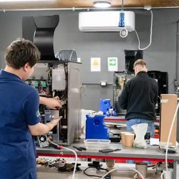 Técnico de Coffee Solutions reparando cafetera en negocio